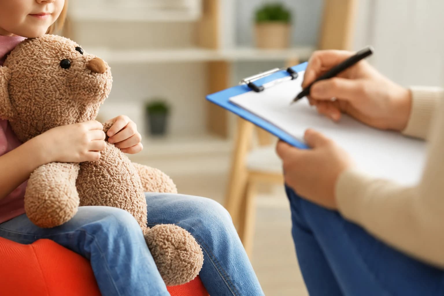 Consultation de neuropsychologie : un enfant tenant sa peluche pendant un entretien, la praticienne prenant des notes.